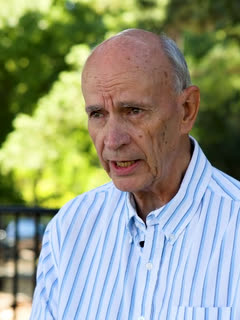 Biff Warren, on a shaded deck behind an iron fence.